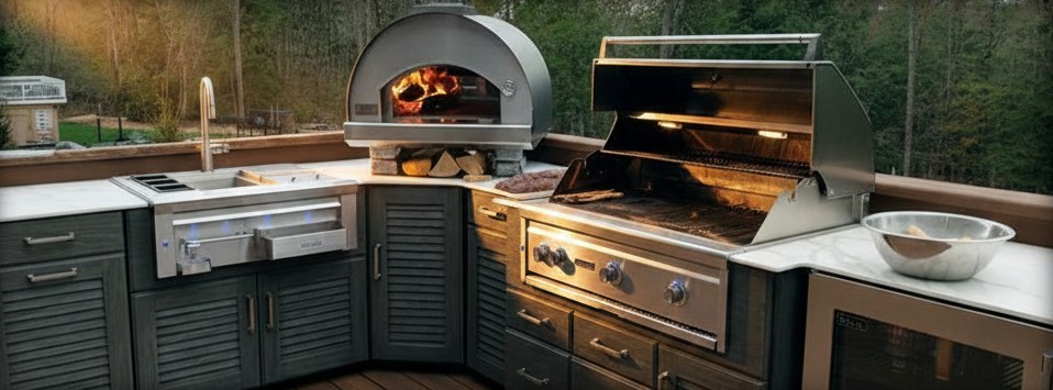 Cucina da esterno ad angolo con lavello, forno a cupola acceso nello spigolo, barbecue e frigorifero, piano chiaro venato