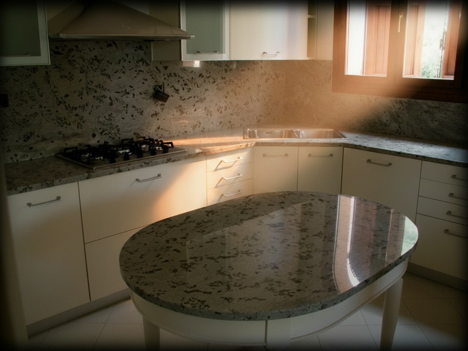 Cucina classica con piani e alzata in granito grigio, isola ovale su base in legno bianco e finestra con scuri in legno