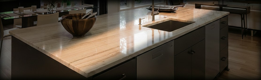 Piano di un'isola in marmo Daino beige con venature ambrate parallele e lavello sottopiano, su basi scure