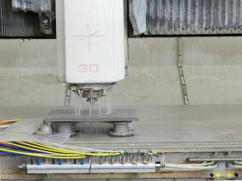 Centro di lavoro CNC lavora una lastra di pietra con getti d'acqua, lavorazione del marmo Michelessi