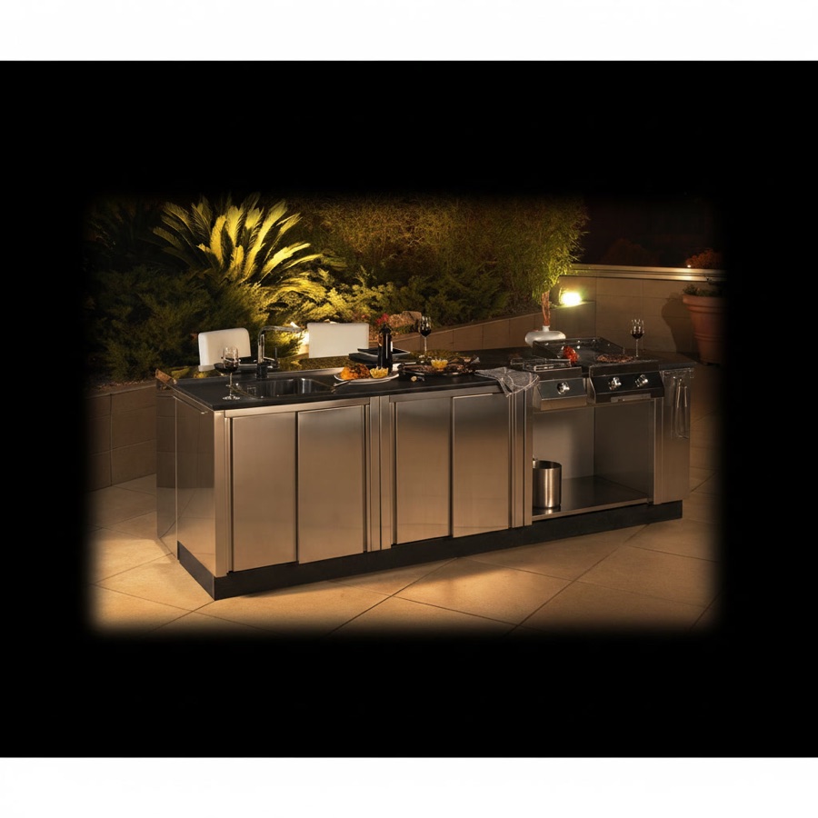Cucina da esterno completamente in acciaio inox con isola e piano scuro, illuminazione serale calda