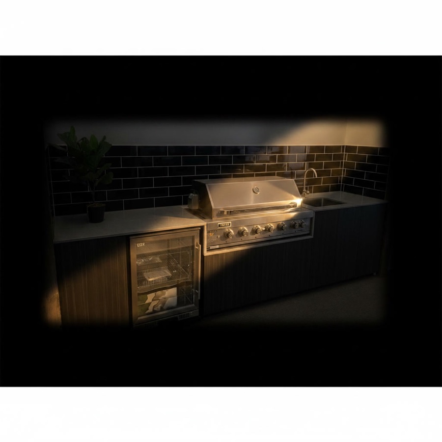 Cucina barbecue professionale da esterno con piano in quarzite, minifrigo con anta in vetro e lavello incassato