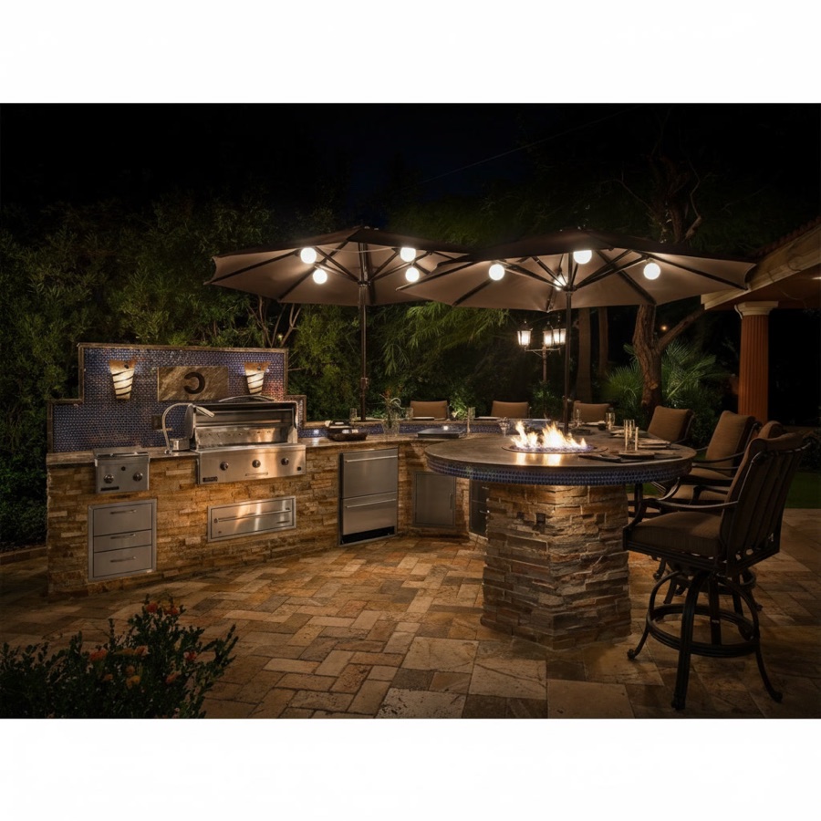 Cucina da esterno in pietra con barbecue a gas con cappa, minifrigo e tavolo rotondo con falò centrale, di sera