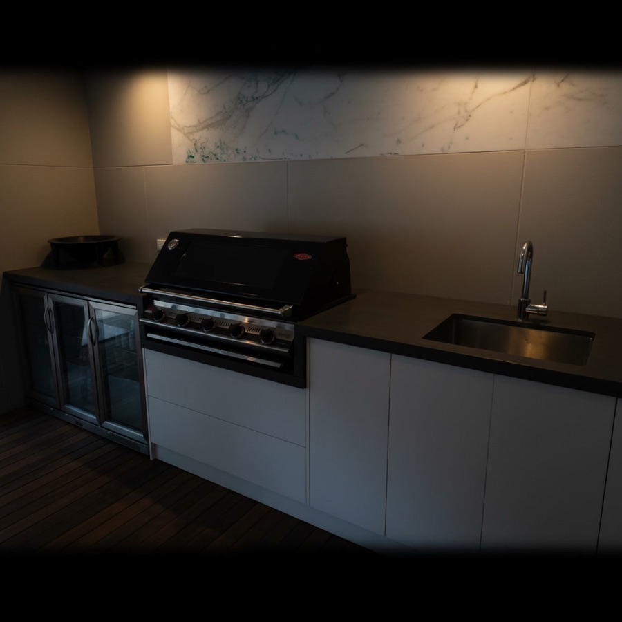 Cucina da esterno completa con pianale sagomato, frigorifero a vista, barbecue incassato e lavello in acciaio