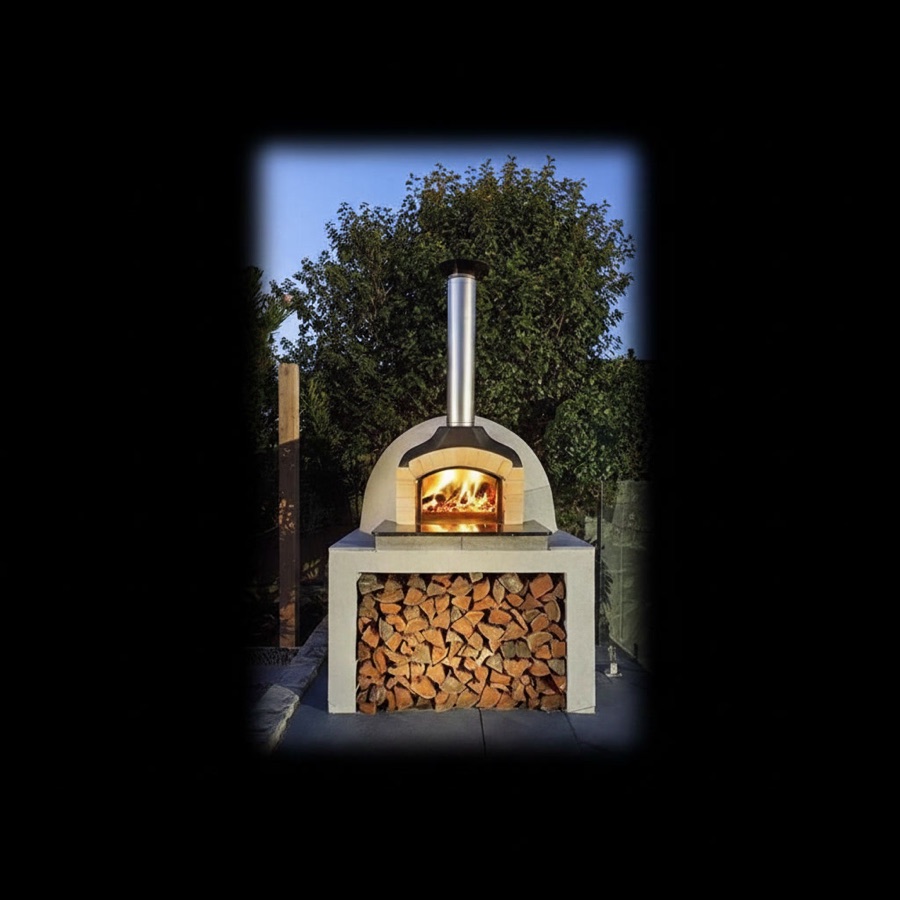 Forno a legna da esterno con fiamma accesa, camino in acciaio e ampio vano portalegna colmo di ciocchi