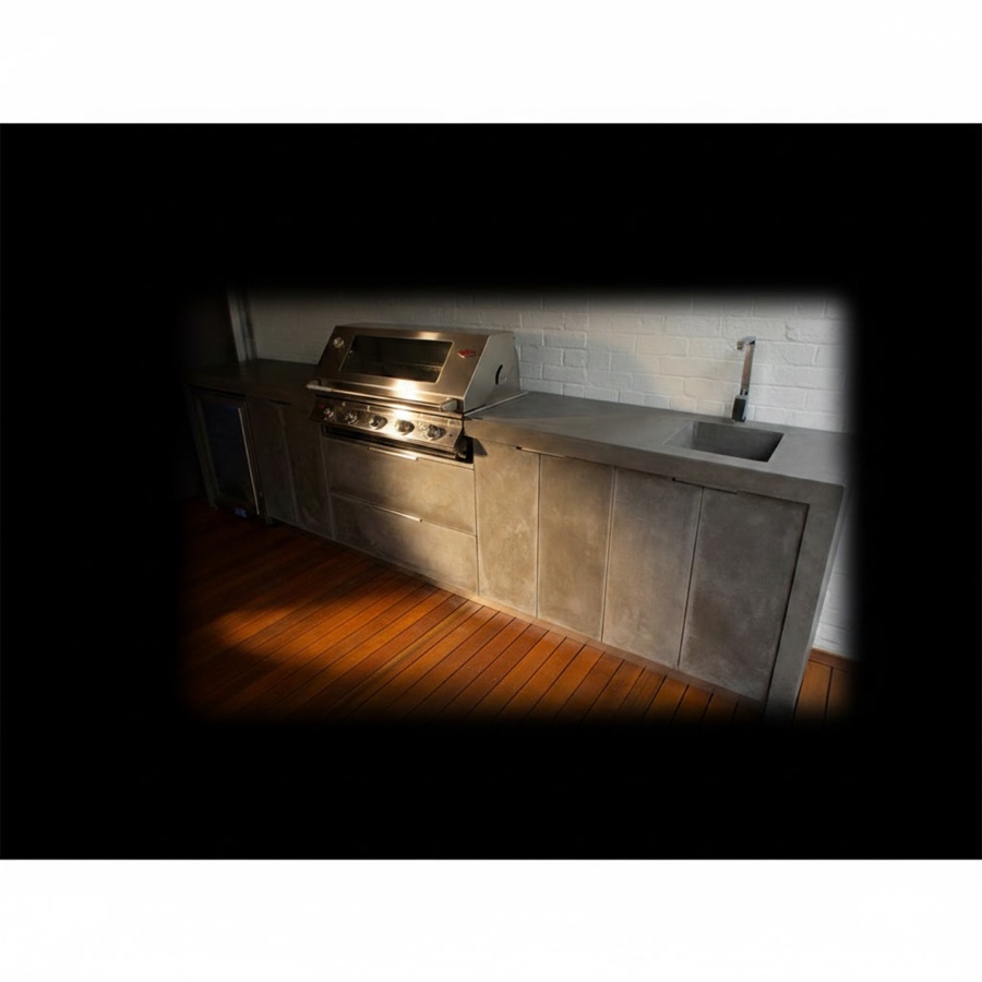 Cucina da esterno con effetto monolite in pietra refrattaria, frigorifero, lavello e barbecue professionale da incasso