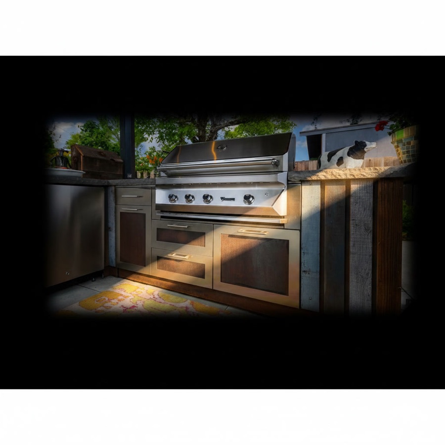Cucina da esterno con piano in pietra a spacco naturale, ante in legno e acciaio con motivi decorativi, barbecue a gas