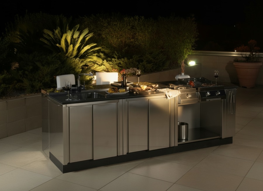 Cucina da esterno Michelessi completamente in acciaio inox con isola centrale, fotografata in notturna