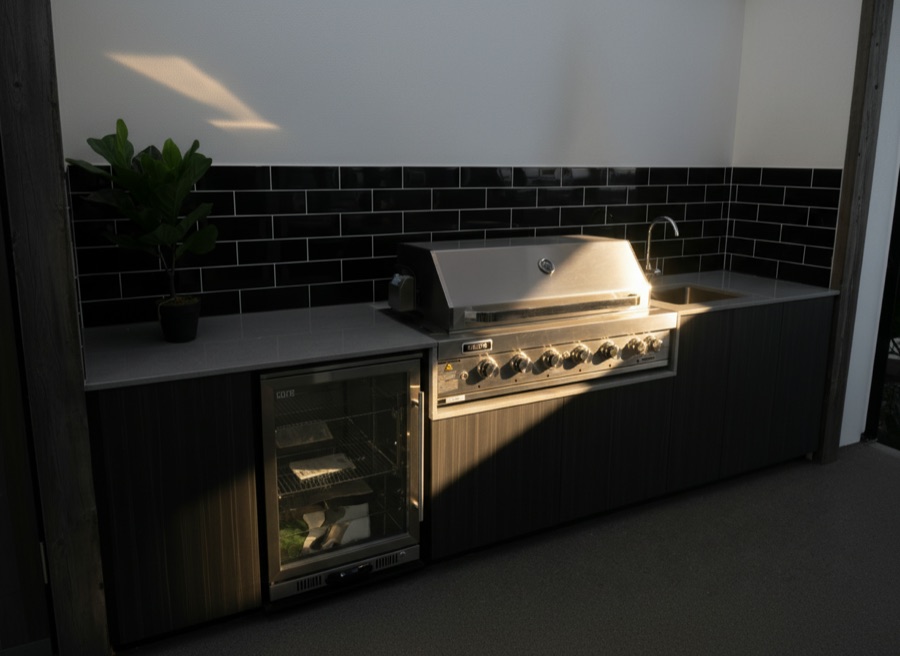 Cucina da esterno con barbecue professionale incassato, minifrigo a vista, lavello e piano in quarzite