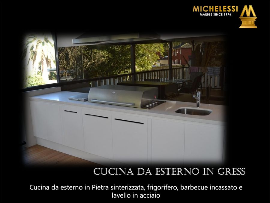 Cucina da esterno in pietra sinterizzata bianca con barbecue incassato, frigorifero e lavello in acciaio, in veranda