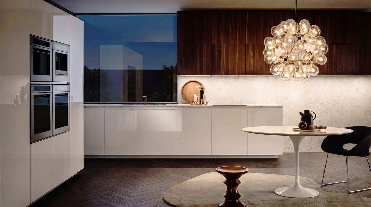 Visione di progetto: cucina moderna con schienale e piano in marmo bianco, basi laccate bianche e pensili in legno scuro
