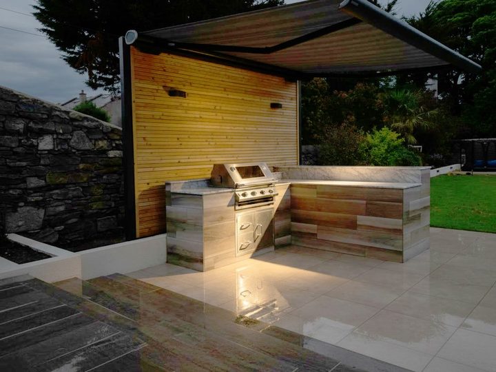 Minimal budget outdoor kitchen with gas barbecue, worktop and aluminium doors beneath an awning