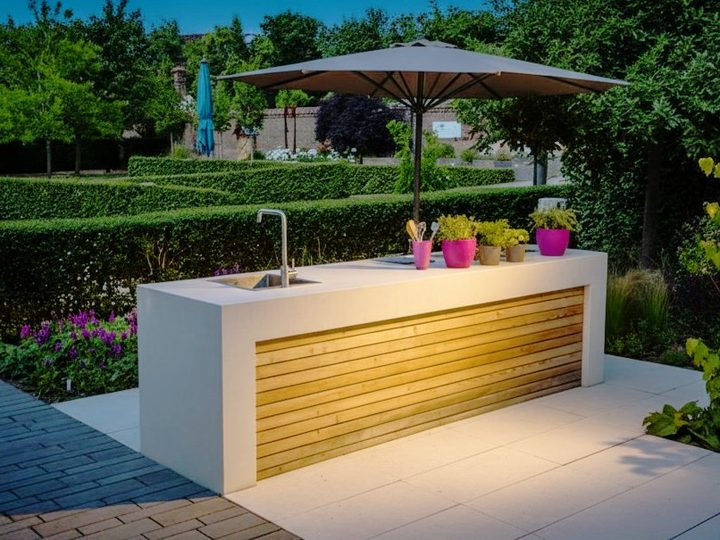 Minimal outdoor kitchen with sink, induction hob and burner, white island with wood band and parasol