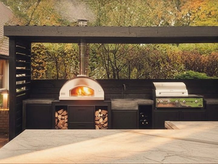 Black bespoke outdoor kitchen with push-to-open doors, gas barbecue, wood-fired oven and sink