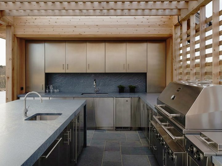 Outdoor kitchen with wooden canopy, stainless steel appliances and cladding, island with sink