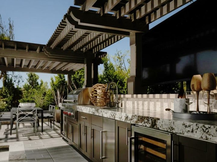 Cucina da esterno con piano in granito, ante in acciaio, cantinetta e barbecue a gas sotto pergola