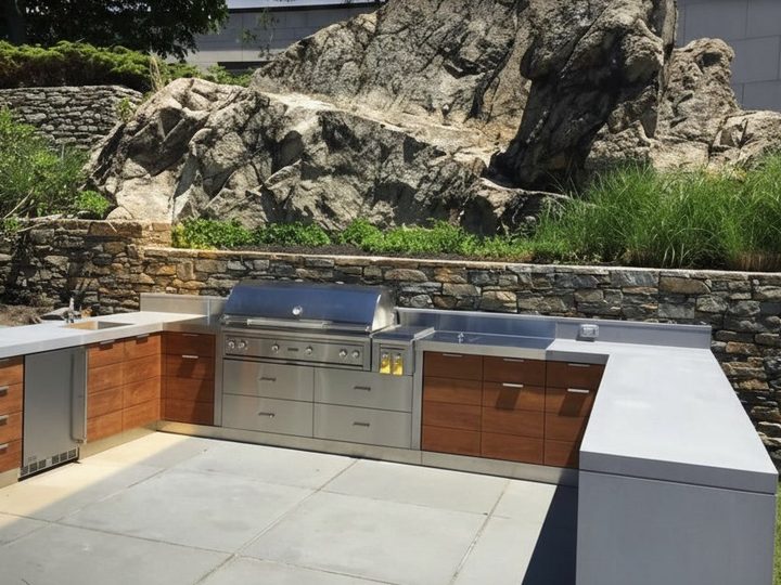 U-shaped maxi outdoor kitchen with sintered stone counter, steel appliances and treated wood doors