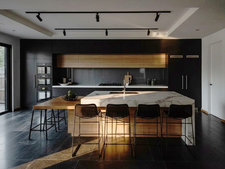 Wooden kitchen with central island with integrated sink, leather stools and integrated fridge