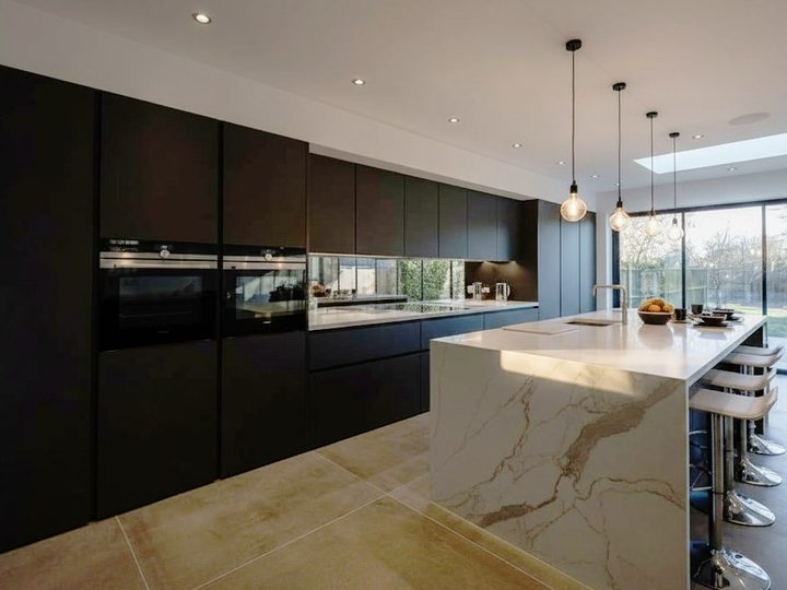 Anthracite wood kitchen with white island with integrated sink, oven, burners and fridge