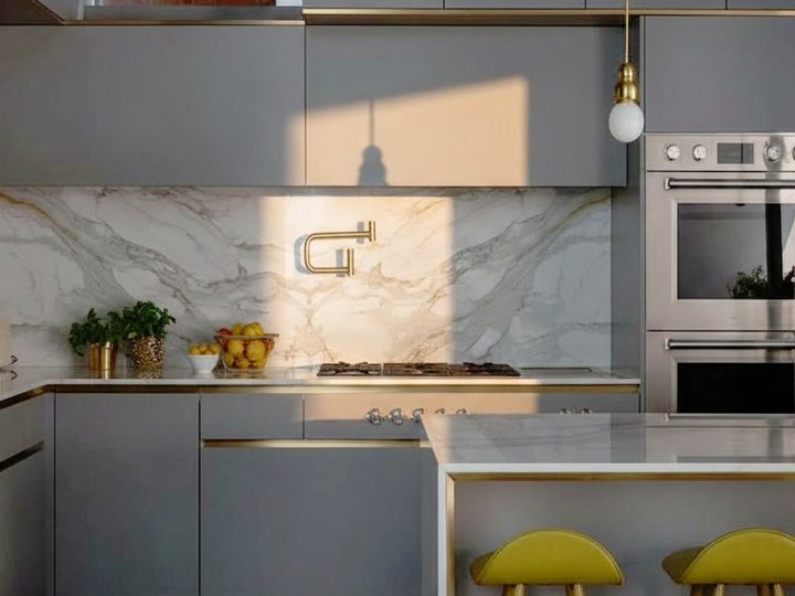 Classic grey kitchen with veined white marble top and splashback, ovens, hob and yellow stools