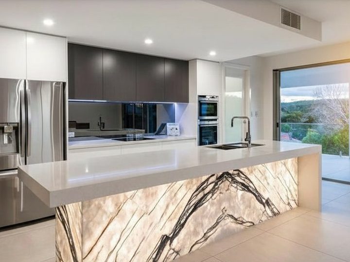 Ultra-modern kitchen with white quartz top and island with backlit book-matched onyx base