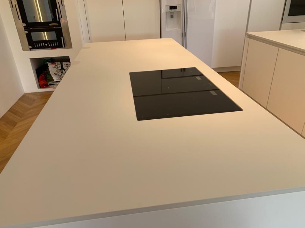 Piano cucina bianco con piano cottura a induzione incassato a filo e parquet a spina di pesce