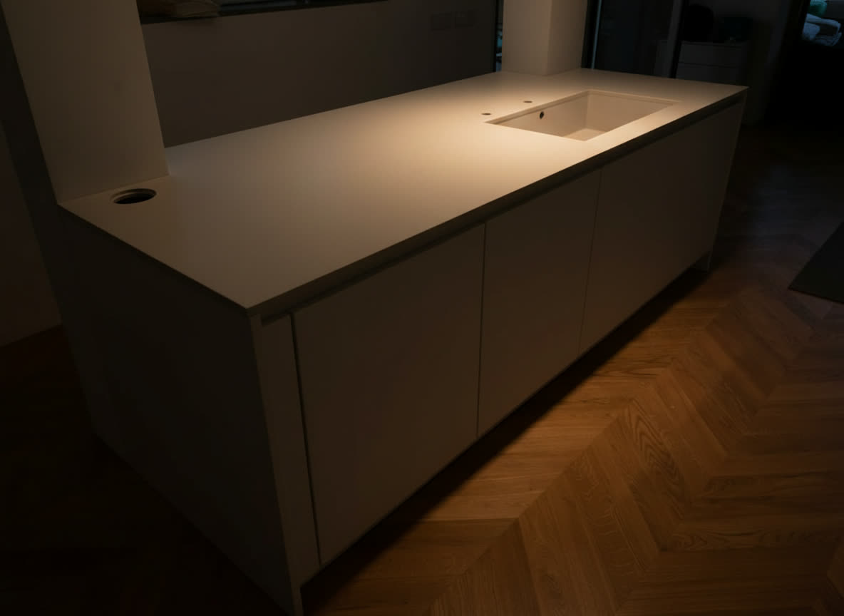 Isola cucina bianca con lavello integrato su parquet di rovere a spina di pesce, montaggio concluso
