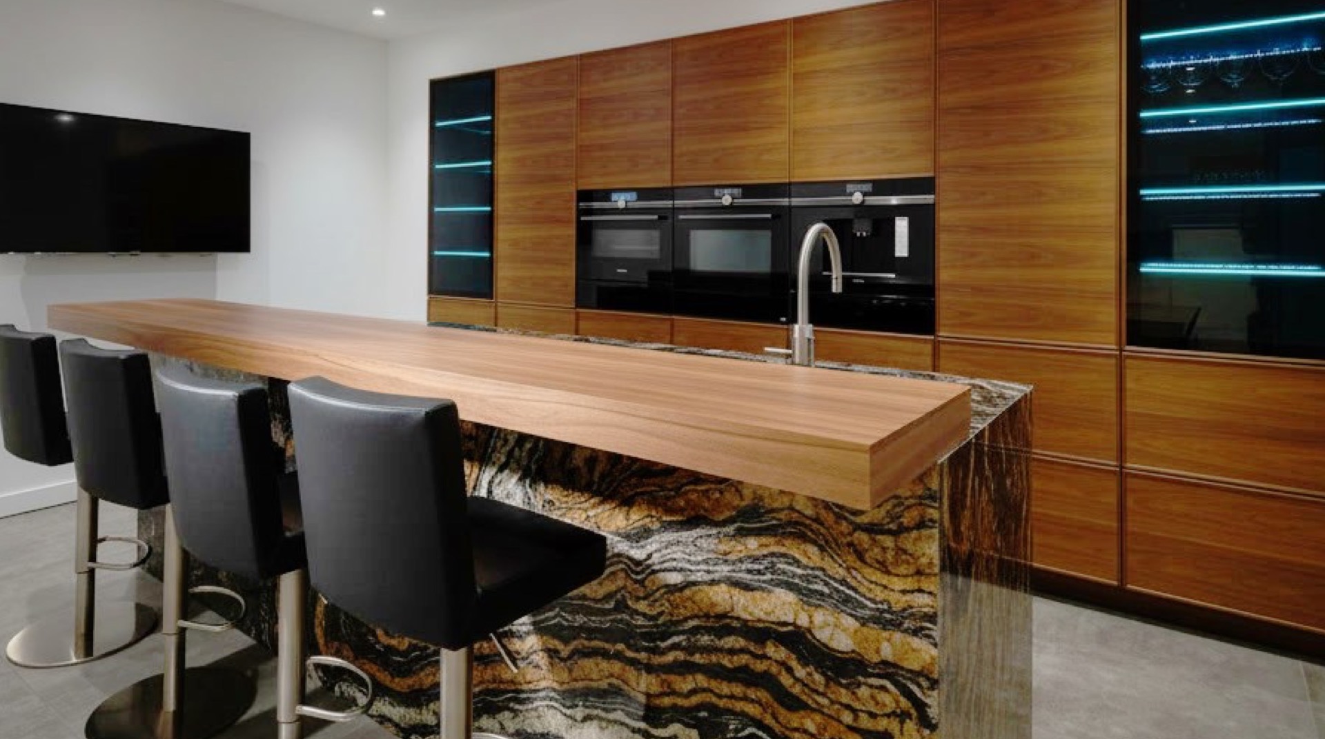 Central quartzite island with spectacular veining, wooden counter and black stools