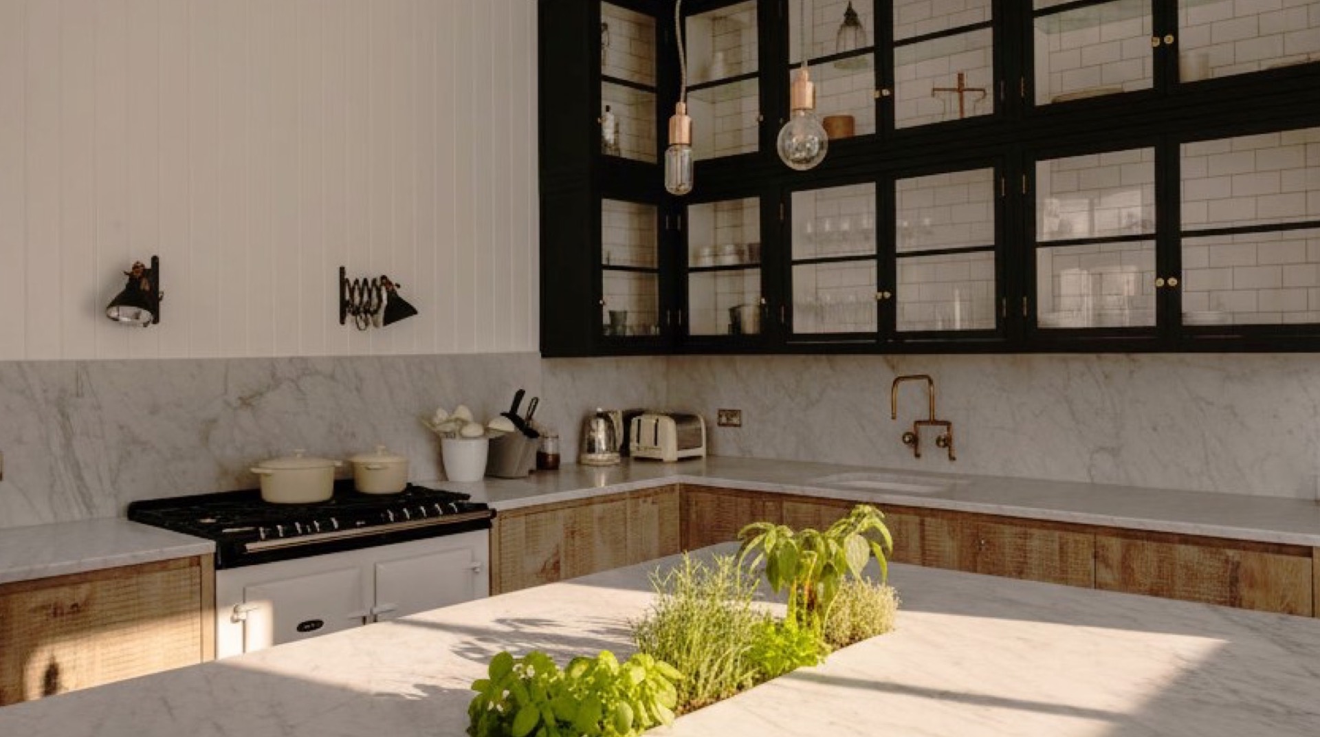 Carrara marble kitchen with contrasting black glass-front cabinets and island with fresh herbs