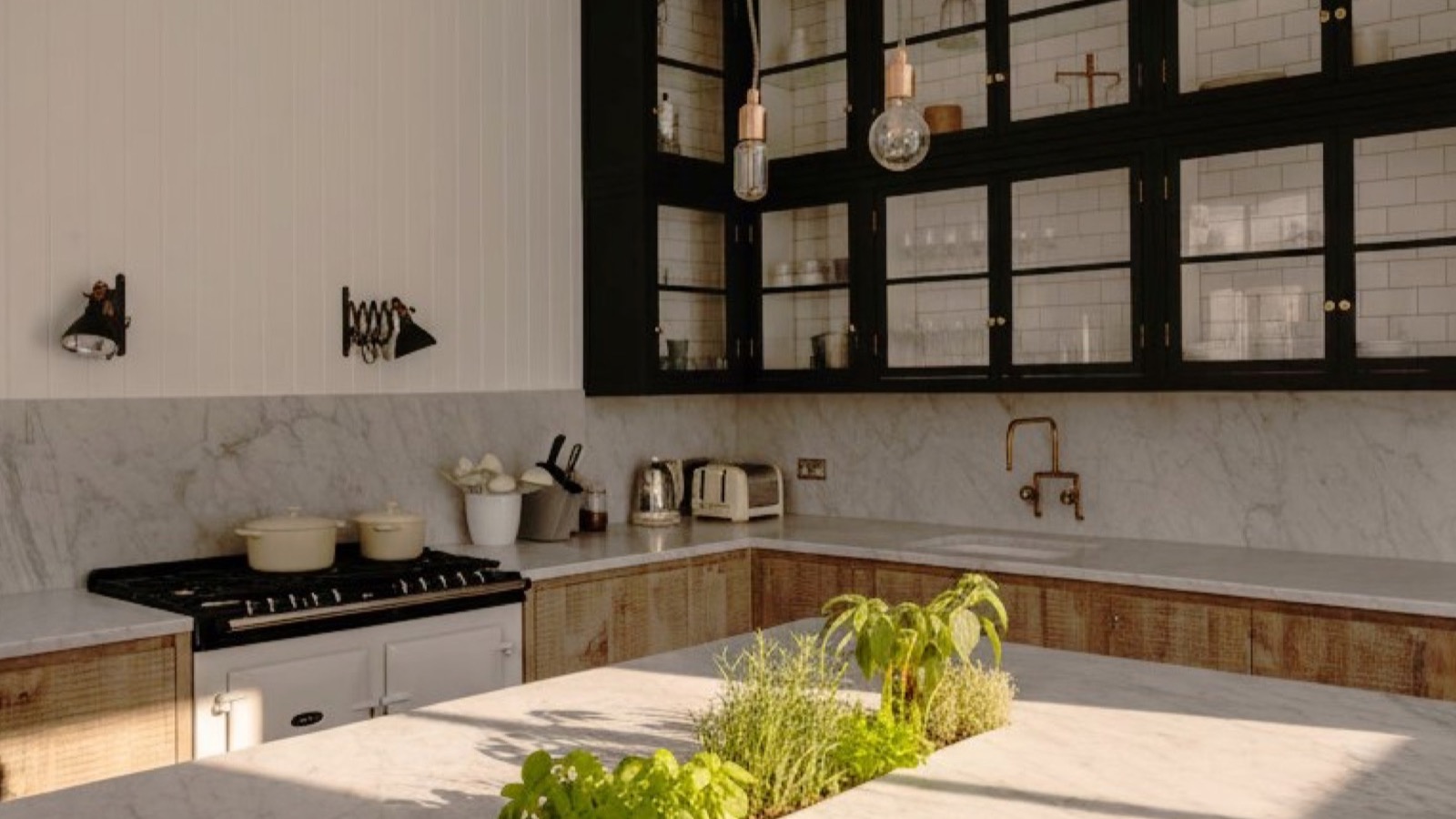 Cucina in marmo di Carrara con pensili a vista neri a contrasto e isola con erbe fresche