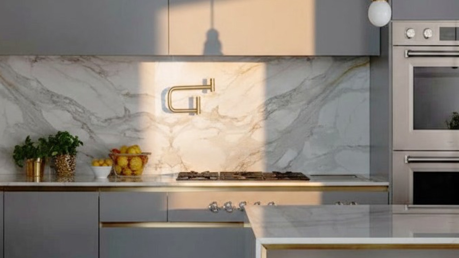 Cucina classica grigia con piano in travertino venato, forno, lavello e sgabelli gialli