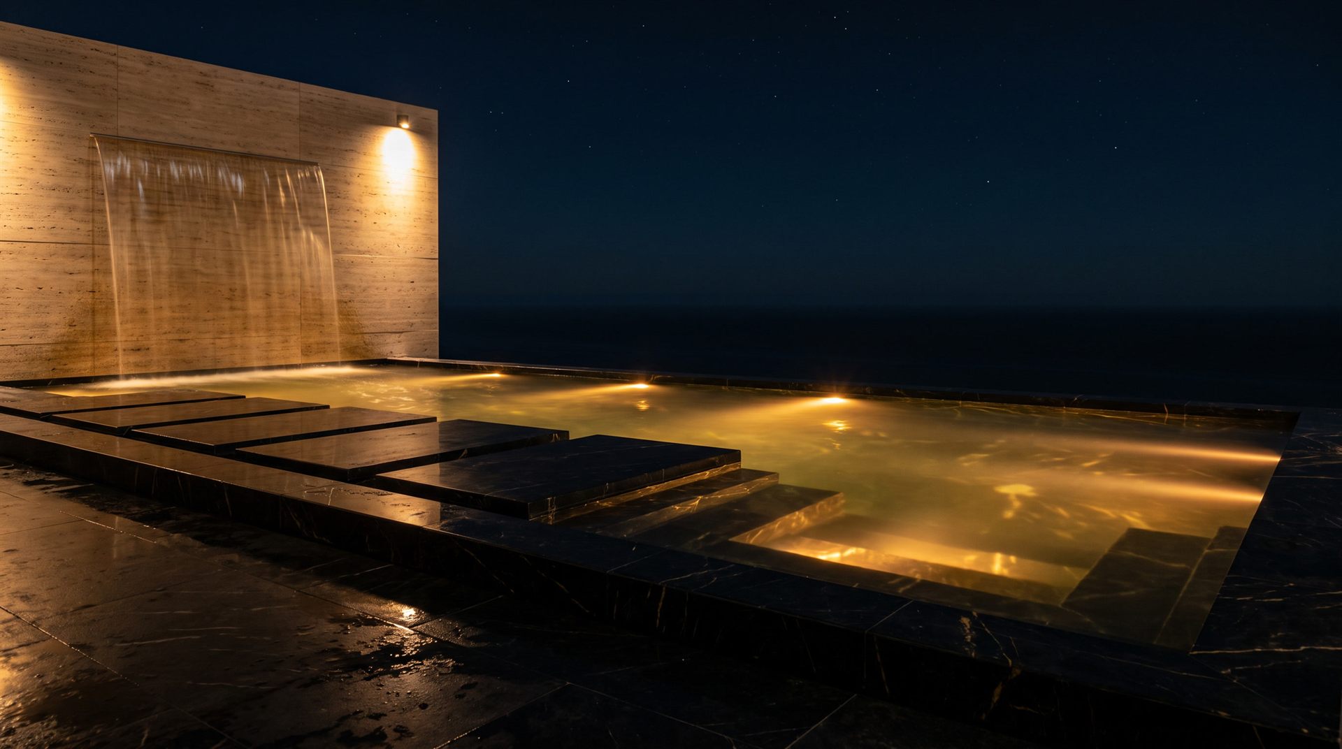 Visione Michelessi: piscina notturna bordata in Nero Marquina con lama d'acqua su parete in travertino, sul mare