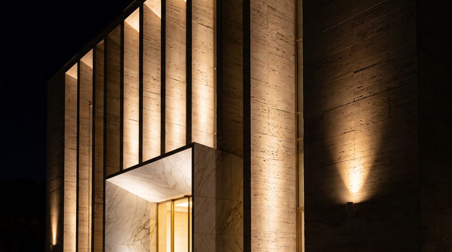 Design vision: facade of vertical Roman travertine fins at night, preview of the building collection