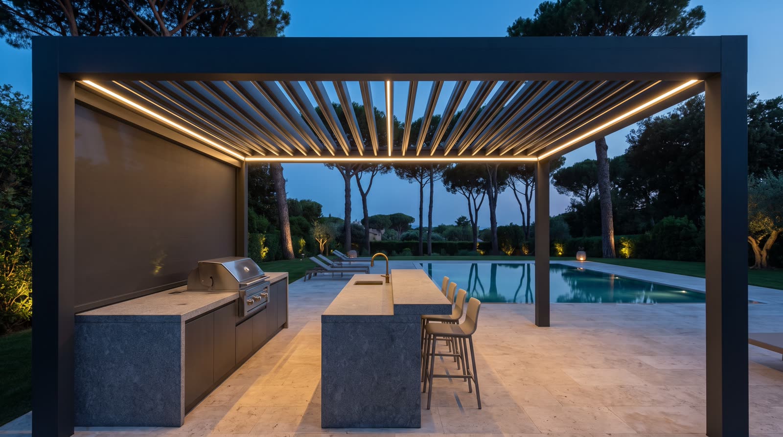 Cucina da esterno in granito e pietra refrattaria sotto una pergola bioclimatica in alluminio antracite, con lame orientabili, luci a led e tenda a zip abbassata, davanti alla piscina al tramonto