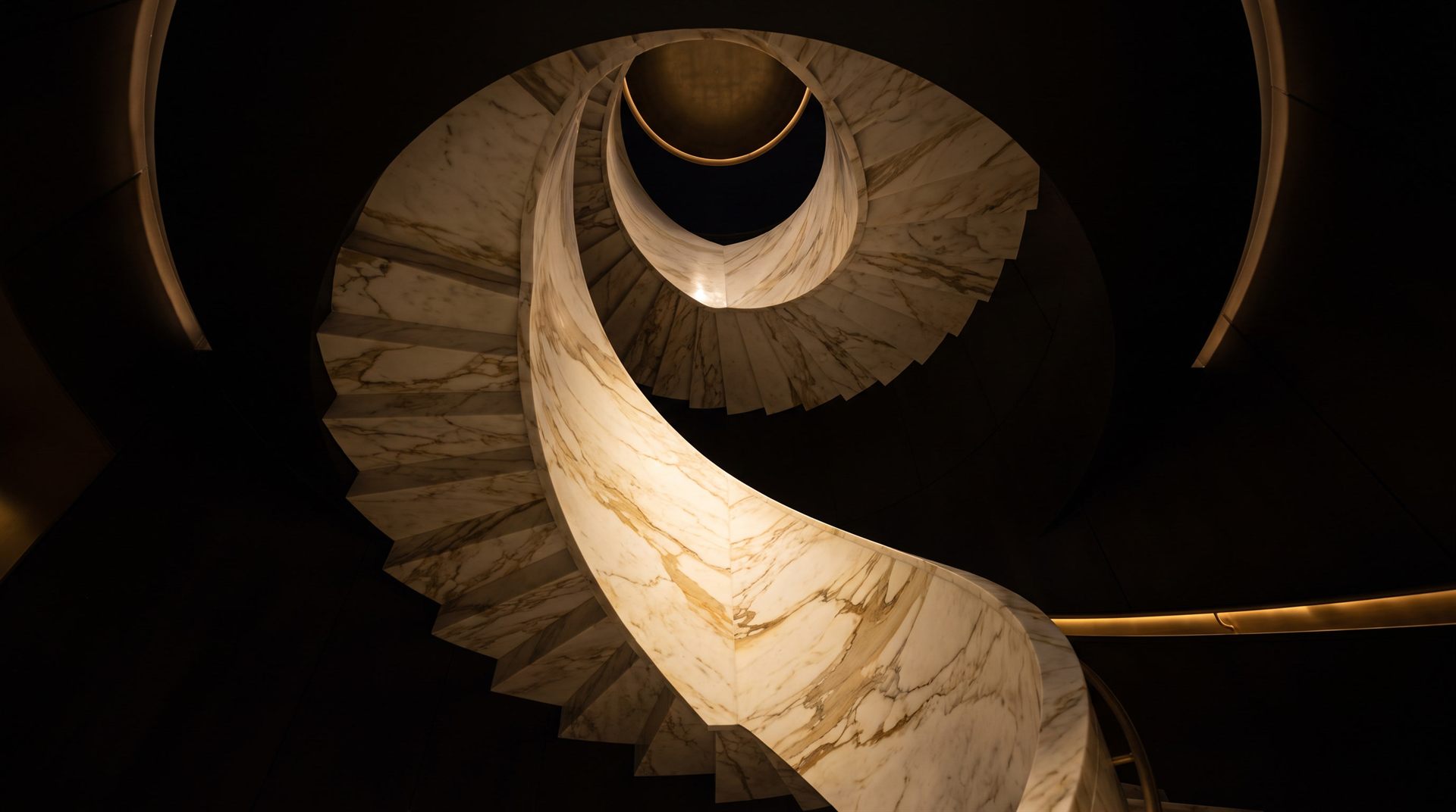 Visione di progetto: scala elicoidale in marmo Calacatta oro senza sostegni, vista dal basso mentre sale a spirale nel buio verso un anello d'ottone